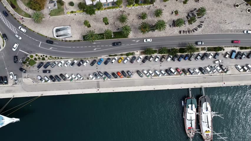 A drone top view of a street with traffic along sea and boats on a port