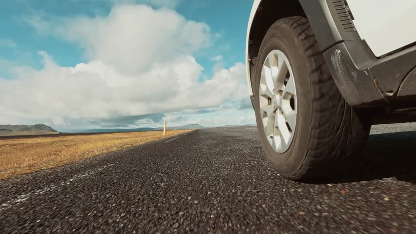 A footage of a running front tire of a car on an empty road in Iceland on a sunny summer day