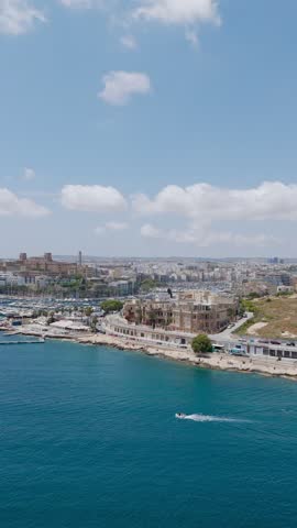 A small motorboat launches from Valletta historic harbor, gliding effortlessly across the calm, blue Mediterranean waters of Malta