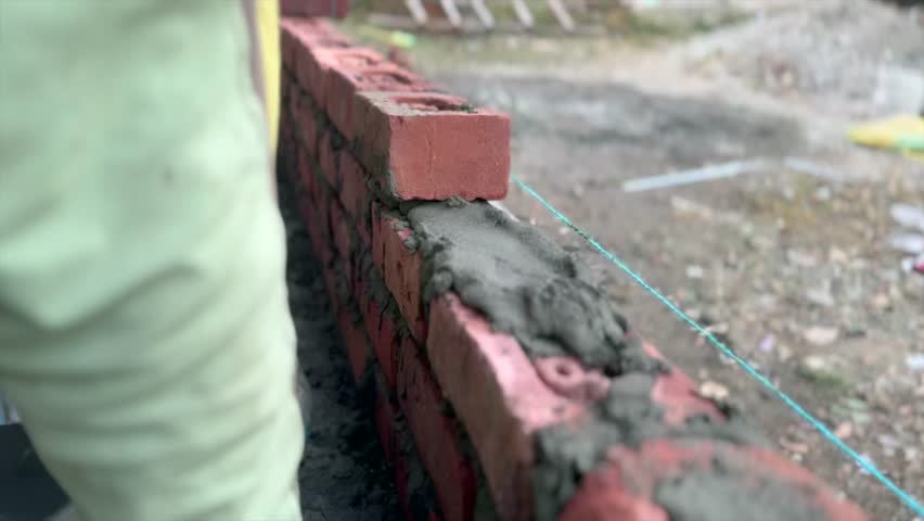Construction of brick wall outside house in a village