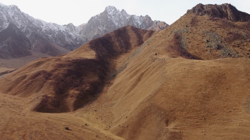 Vast Golden Mountain Landscape with Distant Snow-Capped Peaks