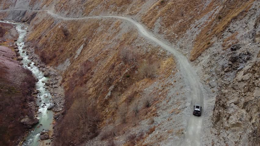 Car Is Riding Winding Road Through a Rugged Mountain Valley