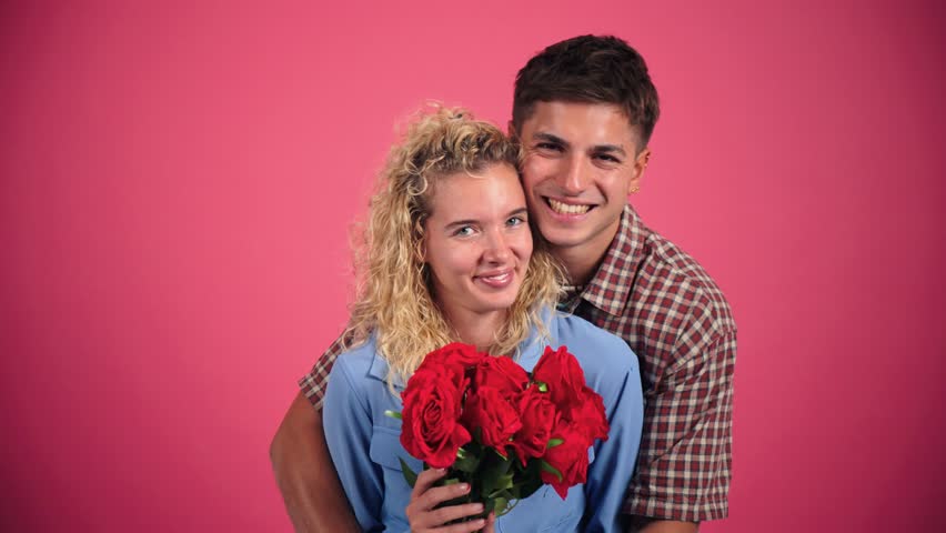 A joyful couple embracing each other while holding a stunning bouquet of red roses, symbolizing their love and happiness together. This image captures the essence of romance and affection beautifully.