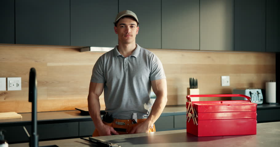 Arms crossed, plumber and face with man in kitchen for home improvement, pipe maintenance and leak detection. Water damage, handyman and inspection with person in house for labor and installation