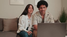 Happy couple relaxing on the sofa, browsing on laptop. They're smiling and pointing at the screen, enjoying their time together at home. - Powered by Shutterstock - Get 15% off with code: PIKWIZARD15