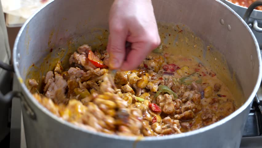 Chef Stirring Large Pot of Cooked Meat and Sauce in Commercial Kitchen