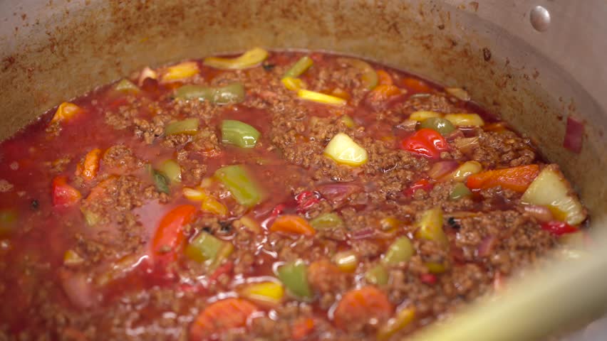 Chef Stirring Large Pot of Cooked Meat and Sauce in Commercial Kitchen