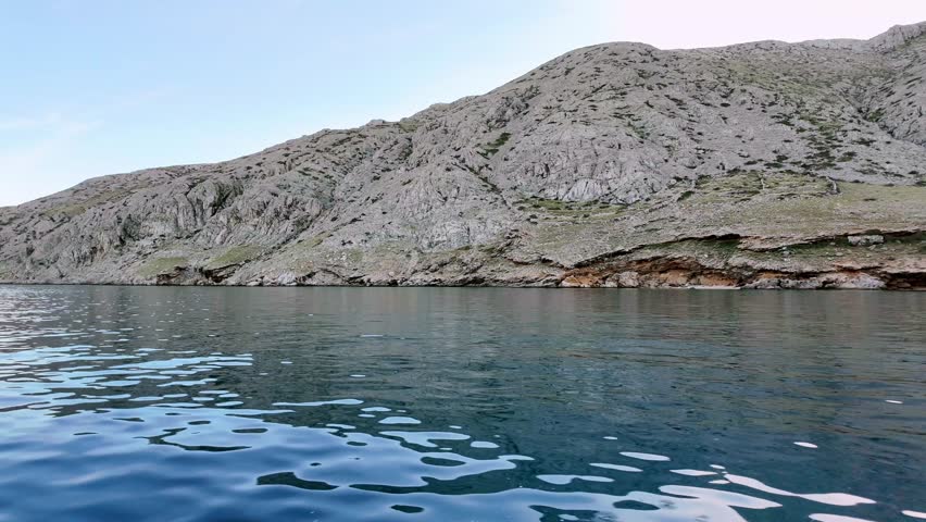 Serene coastal landscape with calm waters and rugged hills under a clear sky. Sea boating adventure.