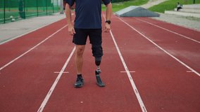 Amputee runner with prosthetic lower limb gear, a running blade, warming up before training, and jumping on an outdoor athletic track, handheld shot. - Powered by Shutterstock - Get 15% off with code: PIKWIZARD15