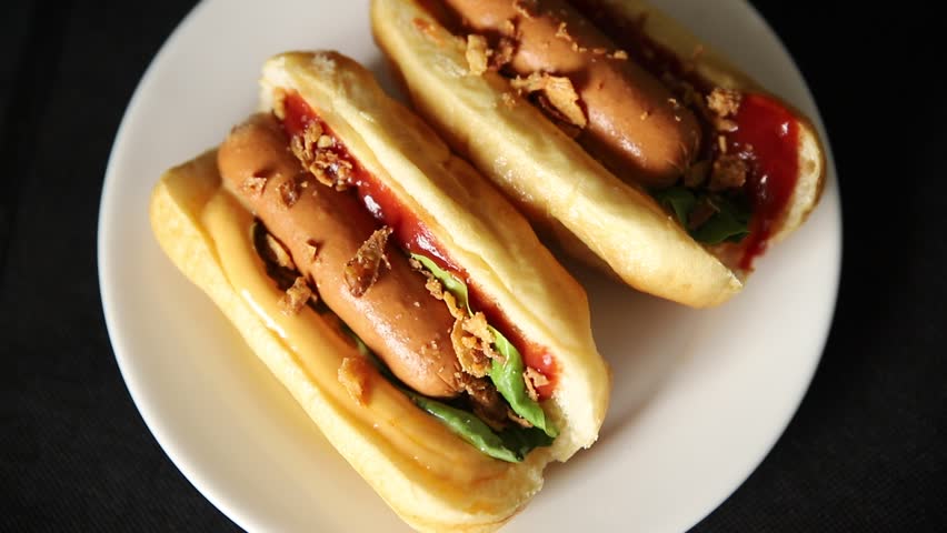 Hot dog fried onions, sausage, bun, sauce fast food tasty snack fresh gourmet food background on the table rustic top view copy space