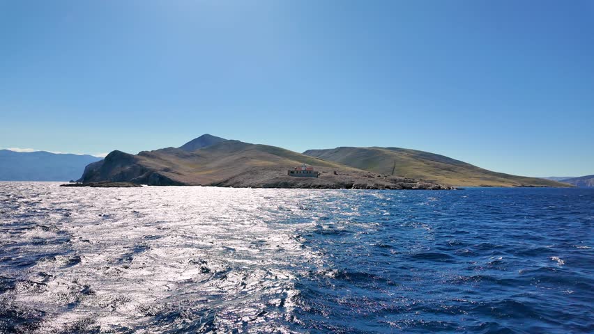 Scenic coastal panorama with ocean waves and sunlit hills under clear sky. Sea boating adventure. View of Prvic island, Croatia.