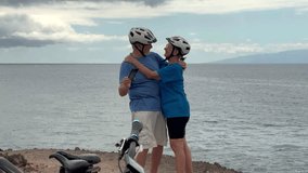 Happy senior couple of cyclists wearing helmets exchange a kiss and take a selfie with phone enjoying riding seaside with electric bicycles. Healthy lifestyle in retirement. Horizon over the sea - Powered by Shutterstock - Get 15% off with code: PIKWIZARD15
