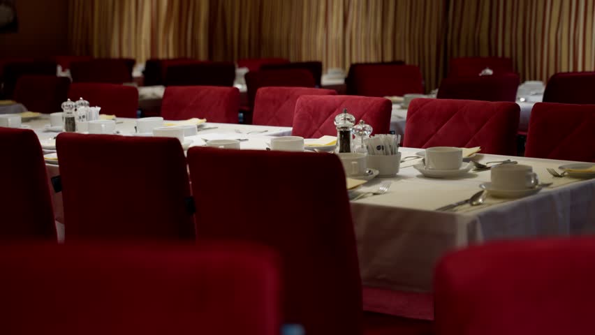 Elegant empty dining room with red upholstered chairs, white tablecloths, teacups and saucers, and striped curtains, set for a formal banquet in a softly lit interior. - Powered by Shutterstock - Get 15% off with code: PIKWIZARD15