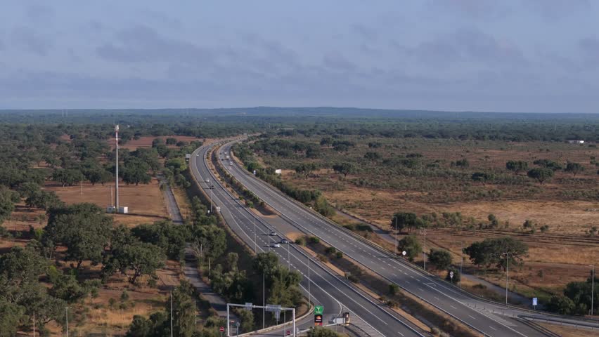 An aerial footage of the A2 motorway connects Lisbon, and the 25 de Abril Bridge to Albufeira in Algarve in Portugal on a sunny day