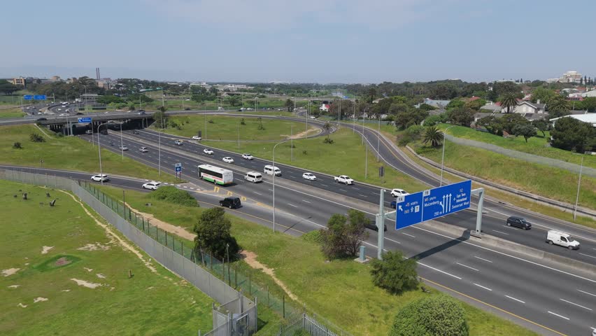 The day traffic on Observatory Road of Cape Town, surrounded by green spaces and houses in South Africa. A bridge seen in the background
