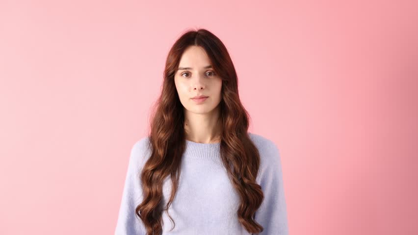 Smiling woman in sweater with candy canes on pink background. Merry Christmas and Happy New Year