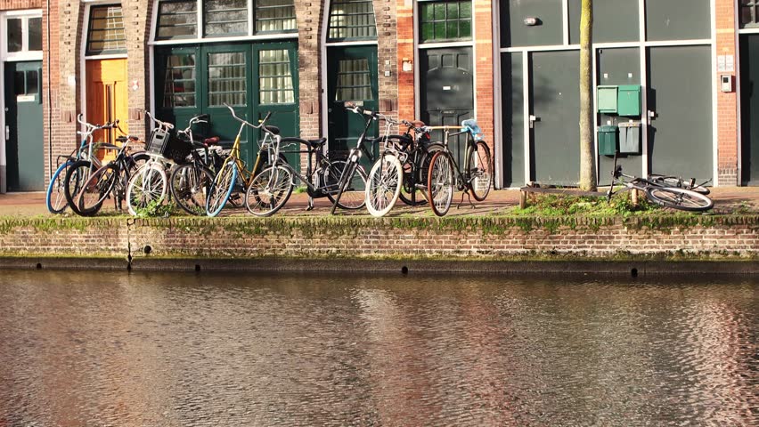 A row of bicycles parked on the canal shore in Leiden city, South Holland province, The Netherlands, on a clear sunny day