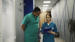 African American doctor and nurse discussing medical case in hospital hallway - Powered by Shutterstock - Get 15% off with code: PIKWIZARD15