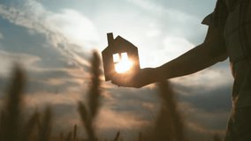 Silhouette of Hand Holding Paper House Against a Sunset Sky - Powered by Shutterstock - Get 15% off with code: PIKWIZARD15