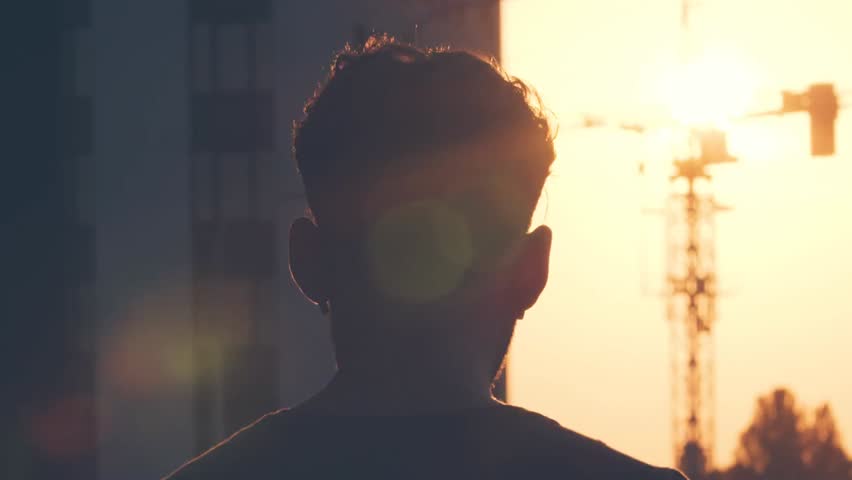 Young person strolling through a city at sunset in slow motion, capturing urban lifestyle, relaxation, and scenic evening atmosphere.