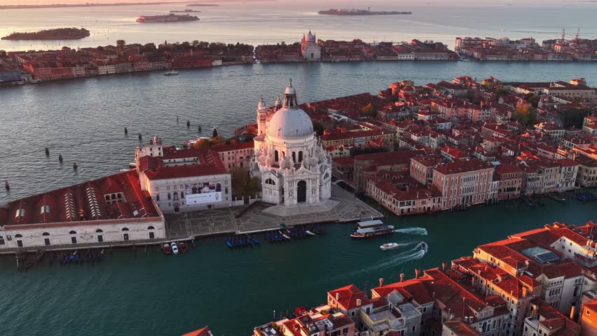 Aerial video of Venice old town at sunrise, tourism in Italy. Basilica di Santa Maria della Salute, Grand Canal and lagoon. Venice skyline at sunrise. Establishing aerial shot of Venice. 