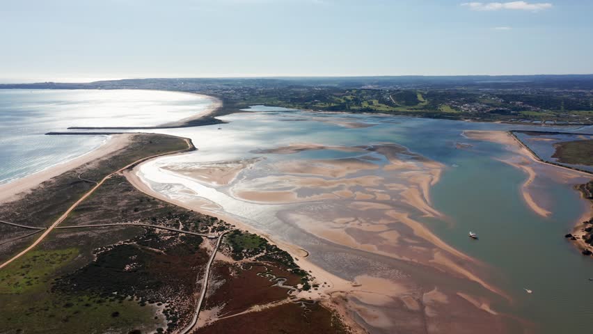 Aerial drone view over Alvor estuary in Algarve, Portugal, showing tidal sandbanks, coastal wetlands, and reflective waters under sunlight. Concept of natural beauty and ecological diversity