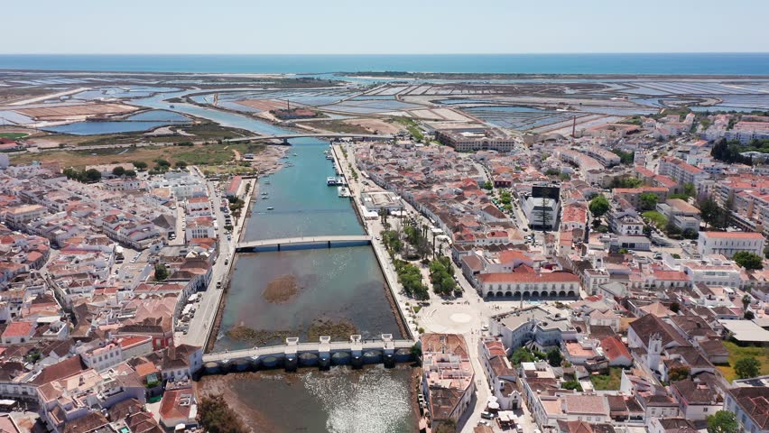 aerial estuary view tavira portugal with visible salterns and tidal channels, nature documentary shot showing marshes, mudflats, wildlife habitat and long coastal approach to sea