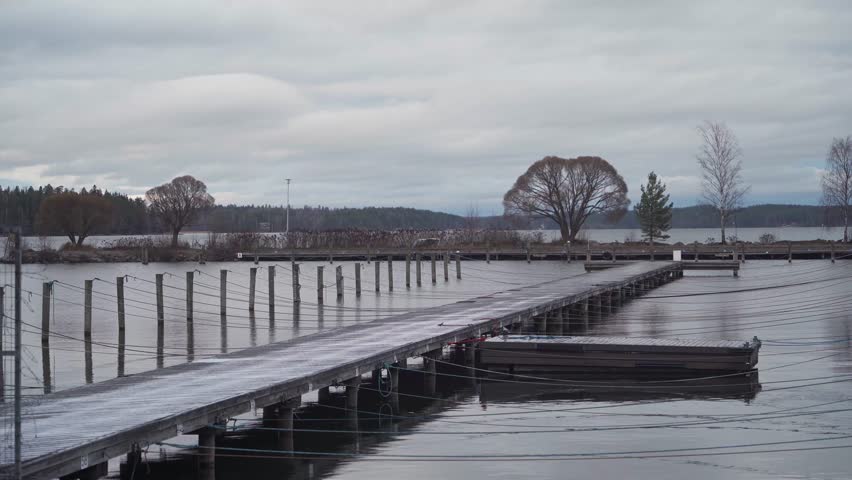 Wooden dock in an empty harbor covered in the first snow of late autumn in Hollola, Finland.