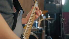 The guitarist is focused on playing, in the background is a blurred drummer. In the frame are musical instruments transmitting the energy of the band's rehearsal. Close-up - Powered by Shutterstock - Get 15% off with code: PIKWIZARD15