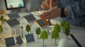 A design engineer works with a calculator, analyzing solar panel layouts on model houses. This scene takes place in an office dedicated to renewable energy solutions - Powered by Shutterstock - Get 15% off with code: PIKWIZARD15