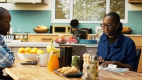 African American couple managing finances sitting at the kitchen table. Checking paperwork and bills or invoices, using laptop for easy money management, financial planning at home. Camera B. - Powered by Shutterstock - Get 15% off with code: PIKWIZARD15