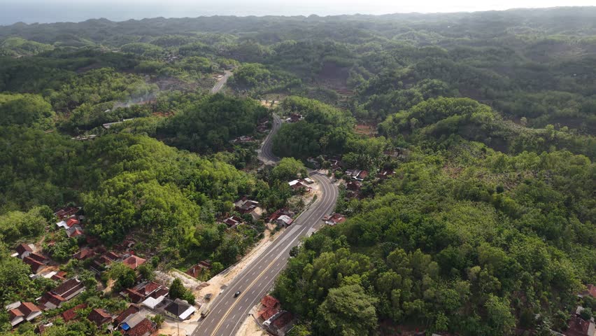 An aerial view of the southern ring road of Java Island, located in Gunungkidul, Yogyakarta. The route passes through small mountains. High quality 4k footage