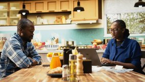 African American couple managing finances sitting at the kitchen table. Checking paperwork and bills or invoices, using laptop for easy money management, financial planning at home. Camera A. - Powered by Shutterstock - Get 15% off with code: PIKWIZARD15