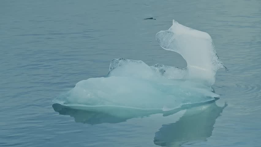 A stunning shot of a small iceberg floating peacefully in the turquoise glacial waters of Jökulsárlón, Iceland.