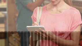 Woman checking spiral notepad with blue pen, writing list in grocery aisle, charts overlaying scene. Shopper, planning, notes, graphs, data, retail, store - Powered by Shutterstock - Get 15% off with code: PIKWIZARD15