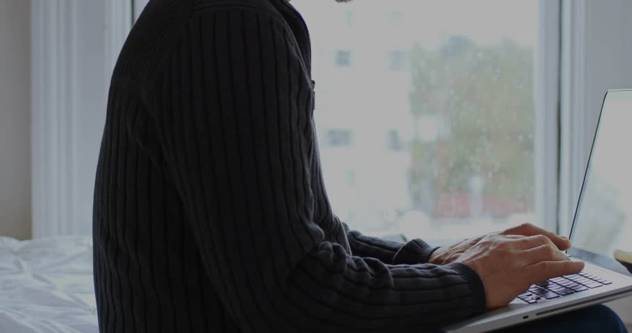 Mature man typing on laptop near window, spawning floating social badges showing engagement surge. Remote, notifications, alerts, screen, concentration, homeoffice, daylight
