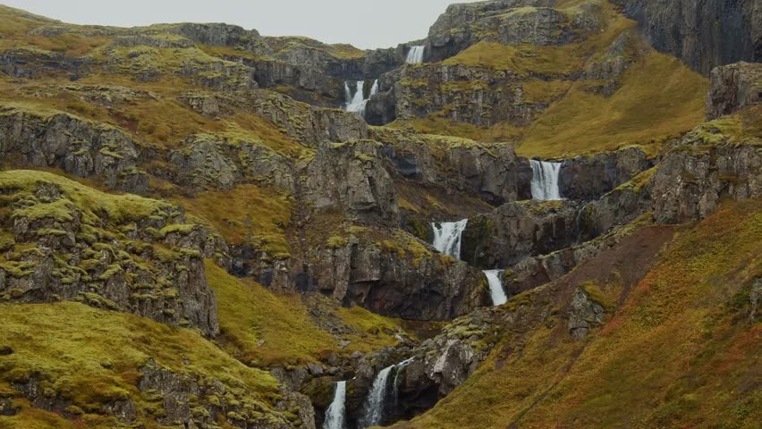 drone footage captures the multi tiered cascades of Klifbrekkufossar, a magnificent waterfall in the remote Mjóifjörður fjord of East Iceland.