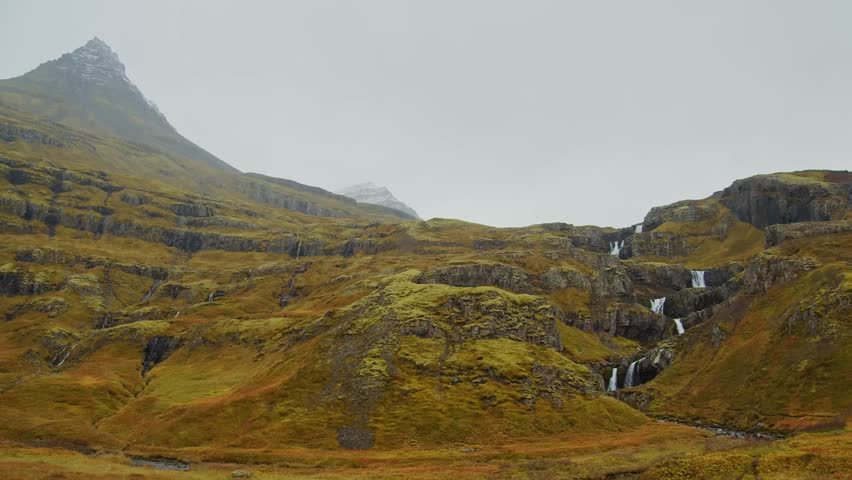 drone footage captures the cascades of Klifbrekkufossar, a spectacular multi tiered waterfall nestled in the rugged and remote landscape of Mjóifjörður, East Iceland