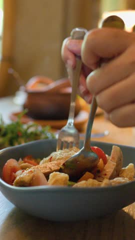 Mixing spicy Thai noodle salad with crispy pork skin in a warmly lit restaurant.
