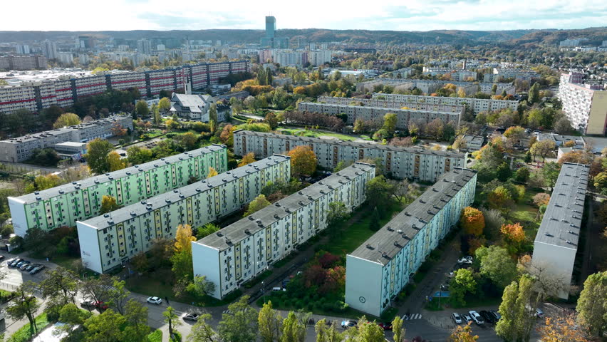 Aerial view of large residential blocks surrounded by trees, roads and dense urban housing districts in Gdańsk