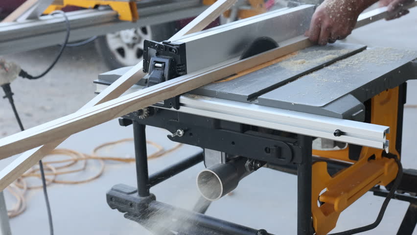 Carpenter is using table saw to cut wood for woodworking project in bright outdoor setting.