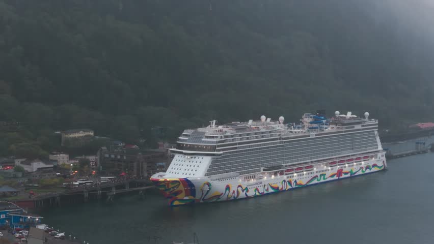 Close-up panning aerial shot of a Norwegian Cruise Line ship docked at the Juneau cruise terminal during a rainy fall day in Alaska. 4K