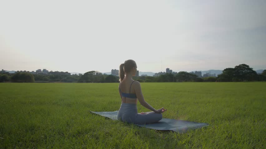 Young woman doing meditation early in the morning in the park.