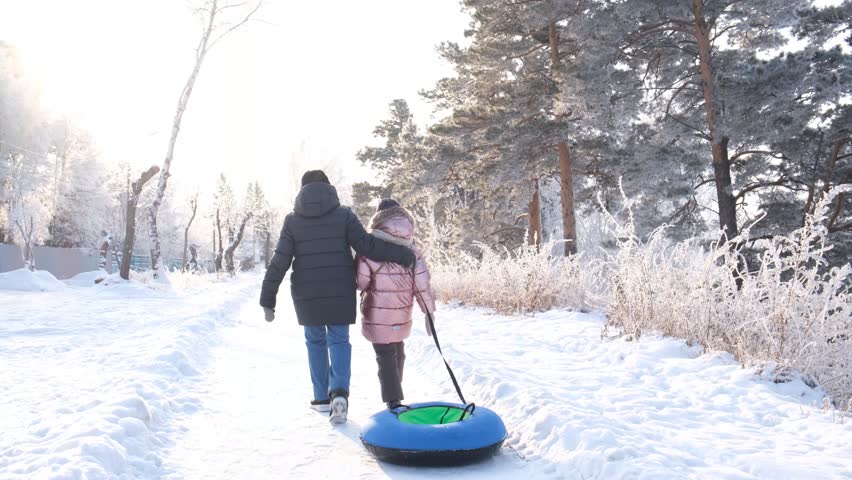 Mother with daughter walking together.  Toboggan hill,  Family outdoors in winter on sledge . Family winter time. Recreational pursuit