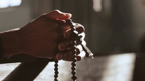Close-up of a male parishioner’s hands holding rosary beads while praying in church, symbolizing faith, devotion, spirituality, and religious practice. - Powered by Shutterstock - Get 15% off with code: PIKWIZARD15