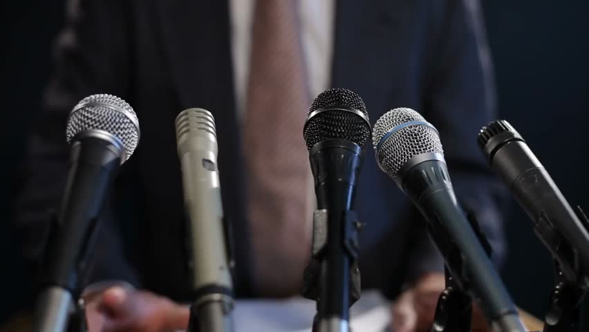 A closeup view of microphones and speakers at a press conference, capturing the atmosphere of media communication, public statements, and official announcements.