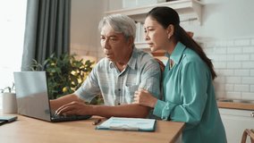 Grandmother comforting and encouraging senior smart manager working and pointing at laptop showing deceasing financial chart. Elder couple helping and talking together while sitting at home. Myrmidon. - Powered by Shutterstock - Get 15% off with code: PIKWIZARD15