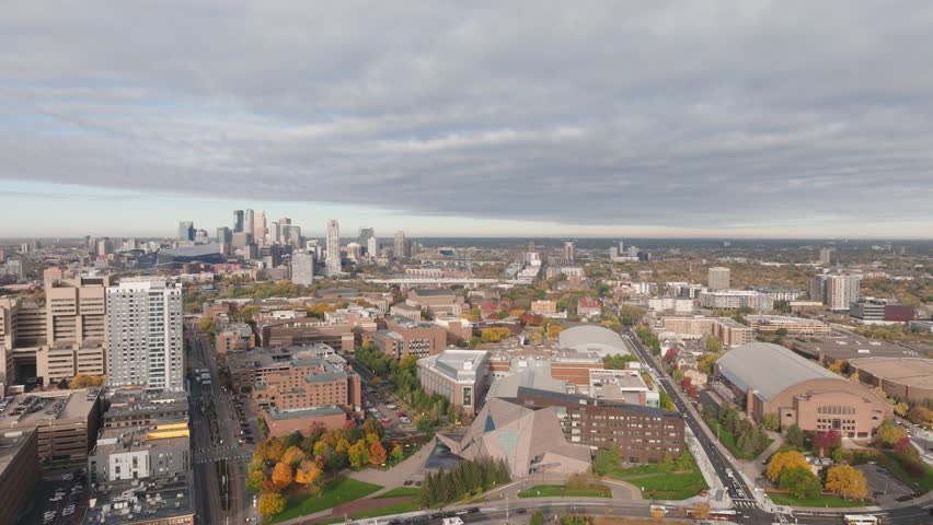 Aerial drone shot over the U of M East Bank campus, featuring the McNamara Center, Williams Arena, and the Minneapolis skyline in the fall.