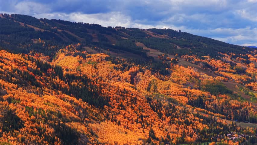 Vail mountain ski resort morning aerial drone parallax fall autumn vibrant colorful quaking aspens trees October blue sky clouds Vail Village ski trails White River National Forest circle left motion
