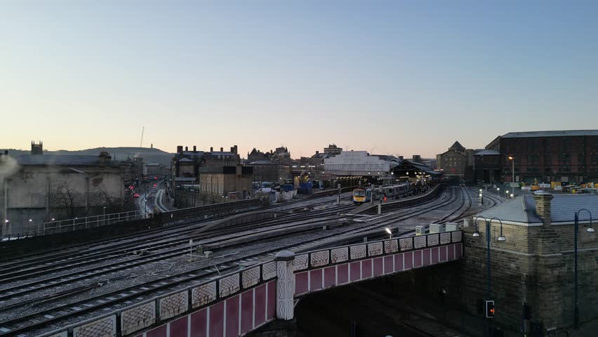 A drone ascending on Huddersfield Train Station and Town Centre at dawn featuring St George